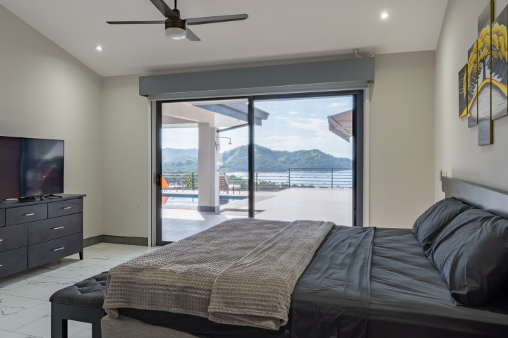 Modern bedroom with large window, mountain view, and balcony.
