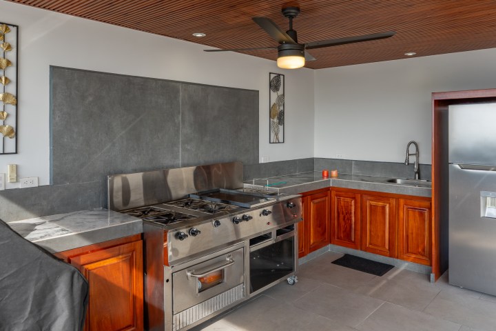 Outdoor kitchen with grill, fridge, and wooden cabinets.