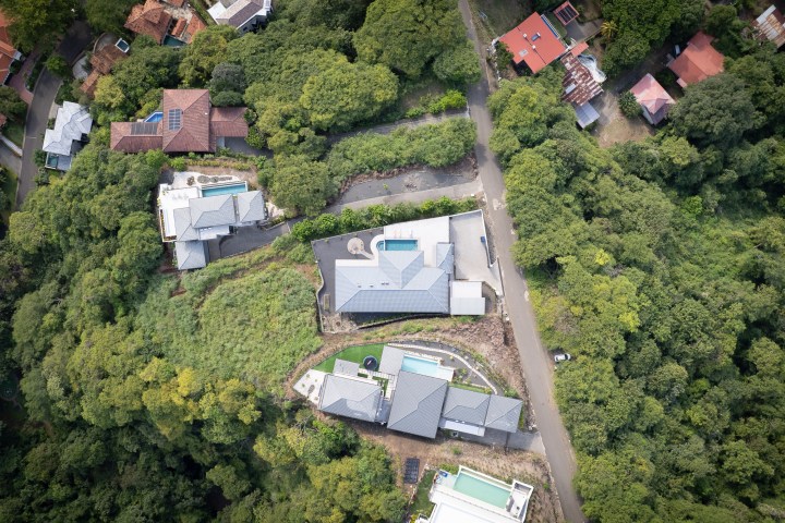Aerial view of houses amidst dense greenery and a road.