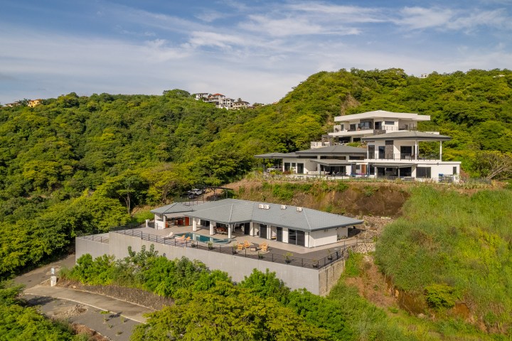Aerial view of modern hillside houses surrounded by lush greenery.