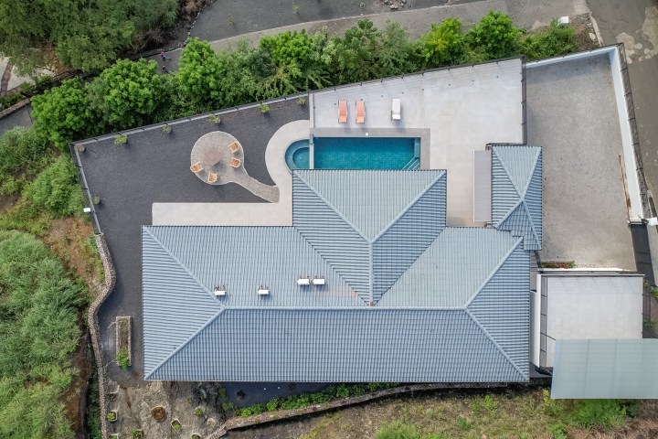 Aerial view of modern house with pool and patio in a lush area.