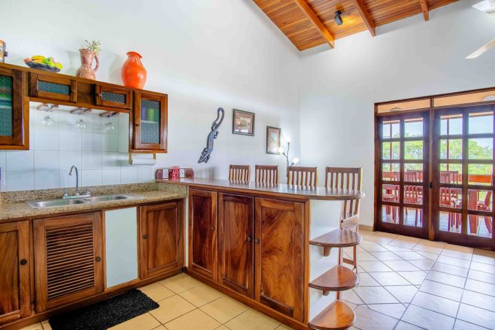 Wood kitchen with bar stools, ceramic floor, and glass patio doors to a balcony.