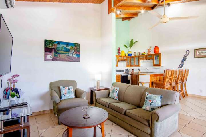 Cozy living room with sofa, armchair, and kitchen bar in open layout.