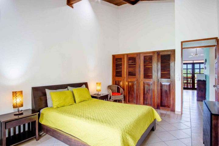 Bedroom with yellow bedspread, wooden furniture, and open door to balcony.
