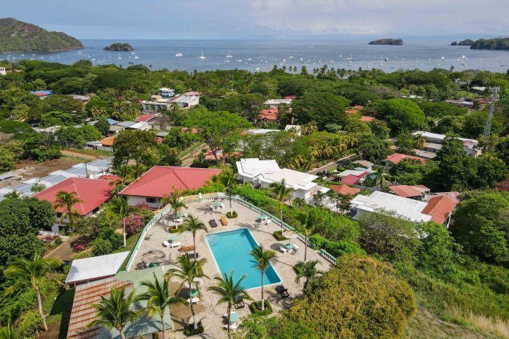 Aerial view of a coastal town with a large pool and ocean in the background.
