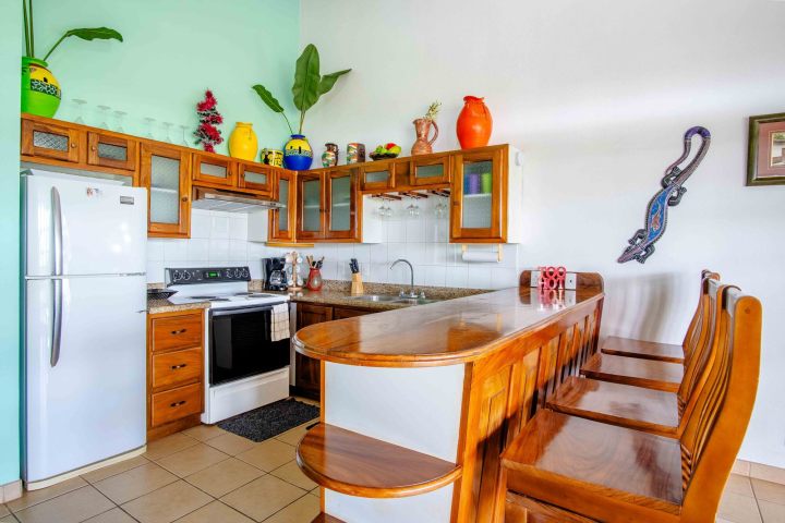 Colorful kitchen with wooden cabinets, bar stools, and decorative vases.